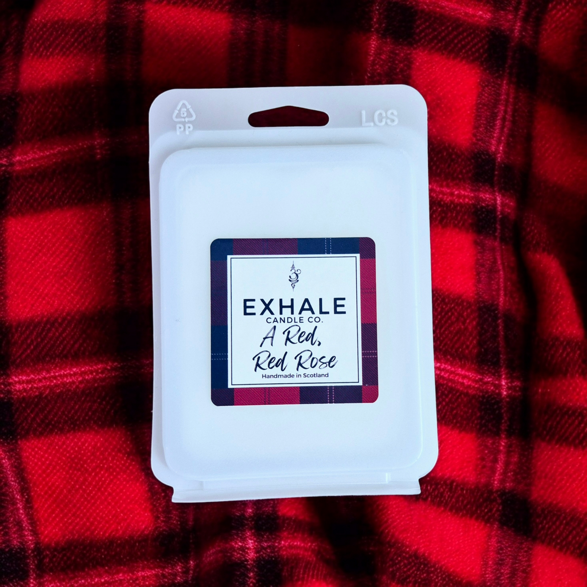 Exhale Candle Co A Red, Red Rose vegan friendly wax melts in a clam shell package on a red and black plaid background.