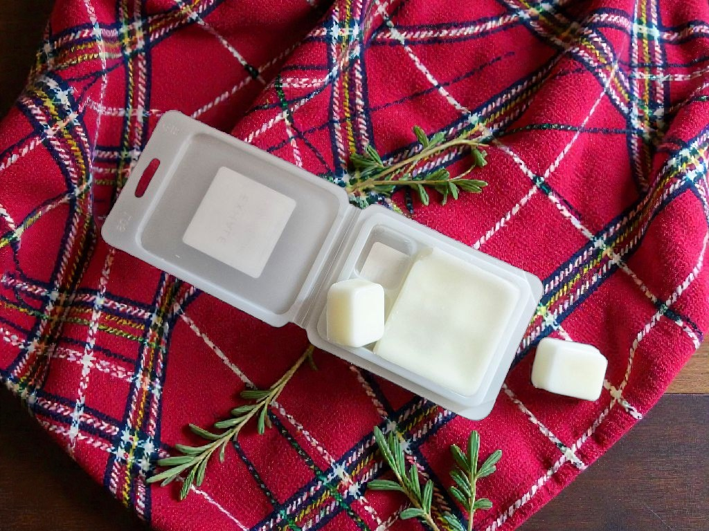 Exhale Candle Co A Red, Red Rose vegan friendly wax melts in a clam shell package on a red and black plaid background.